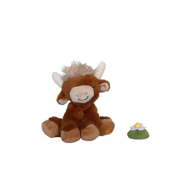 Plush toy cow with a small green and yellow object on a white background