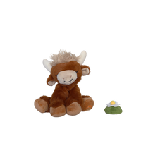 Plush toy cow with a small green and yellow object on a white background
