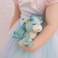 Child holding a plush dragon toy with glittery wings and horns.