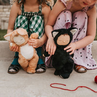 Image of 2 little girls playing with a black cat, soft plush toy doll for kids