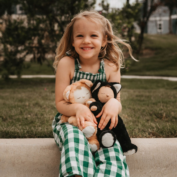Image of a little girl play with a black cat and a tabby cat, soft plush toy doll for kids