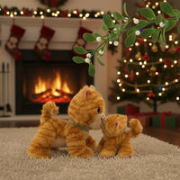 Two plush cats in front of a Christmas tree and fireplace with mistletoe.