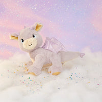 Plush dragon toy with wings on a soft, cloud-like surface with a pastel gradient background.