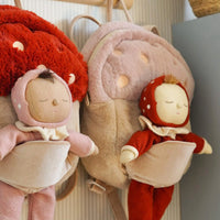 Two plush dolls with red and pink outfits hanging on a rack.