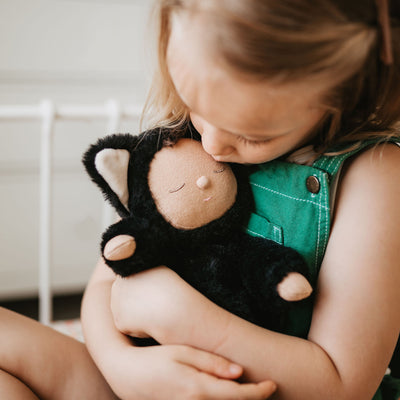 Image of a little girl loving a black cat, soft plush toy doll for kids