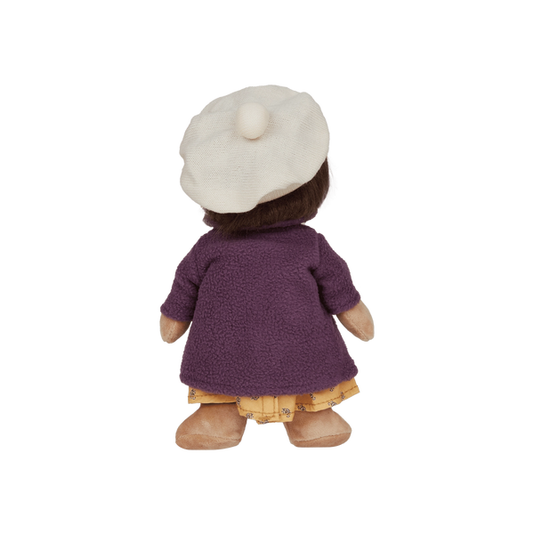 Back view of a doll wearing a purple coat and white hat on a white background