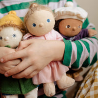 Children holding a group of small dolls with different outfits and hairstyles.