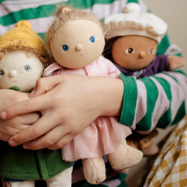 Children holding a group of small dolls with different outfits and hairstyles.