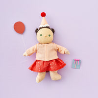 Stuffed doll with a red dress, white hat, and balloon on a light purple background