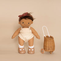 Plush baby doll with brown hair, beige romper, and brown shoes