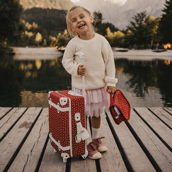 Olli Ella Christmas Theme See-ya Washbag red print pictured with child and suitcase