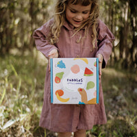 Olli Ella Tubbles Sensory Stones Fantastic Fruit packaging held in child's hands